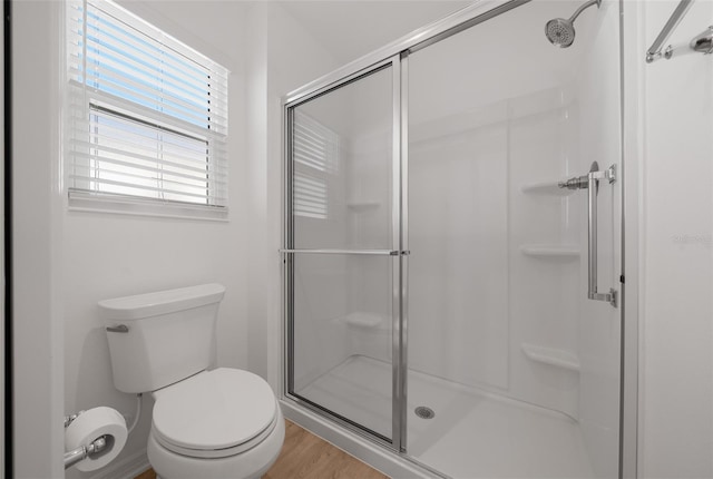 bathroom featuring a shower with door, hardwood / wood-style flooring, and toilet