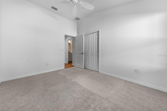 unfurnished bedroom featuring light carpet, lofted ceiling, a closet, and ceiling fan