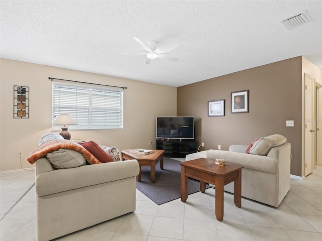 living room featuring ceiling fan, light tile patterned floors, and a textured ceiling