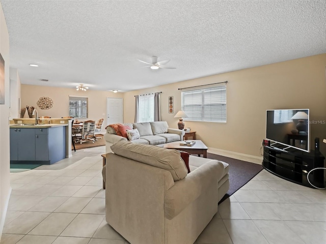 living room with ceiling fan, light tile patterned floors, and a textured ceiling