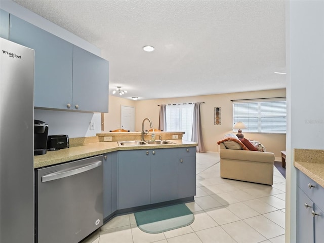 kitchen with sink, appliances with stainless steel finishes, kitchen peninsula, and light tile patterned flooring