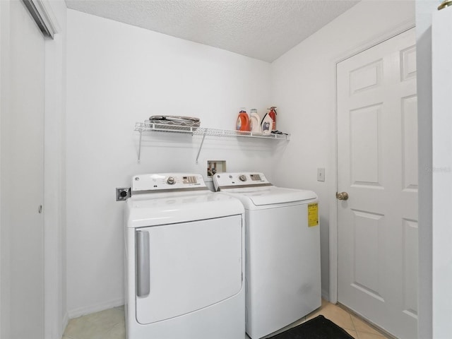 laundry room with a textured ceiling, washing machine and dryer, and light tile patterned flooring