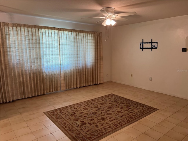 spare room with light tile patterned floors, ceiling fan, and baseboards