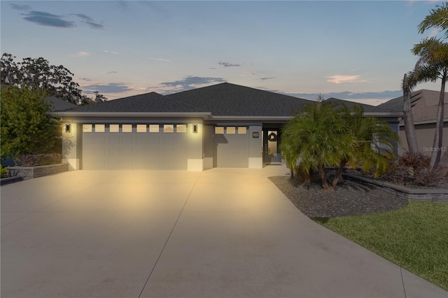 prairie-style house with a garage, roof with shingles, concrete driveway, and stucco siding