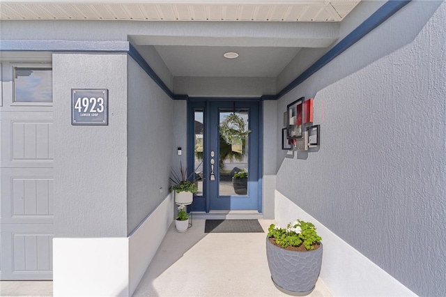 entrance to property with an attached garage and stucco siding