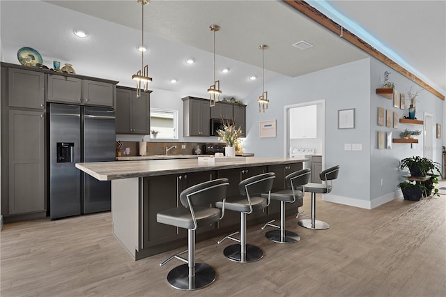 kitchen with a kitchen island, a breakfast bar, decorative light fixtures, light hardwood / wood-style floors, and stainless steel appliances