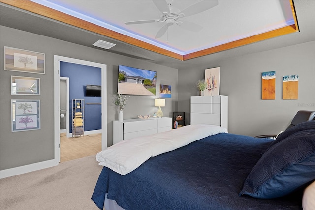 bedroom featuring light carpet, ceiling fan, and a tray ceiling