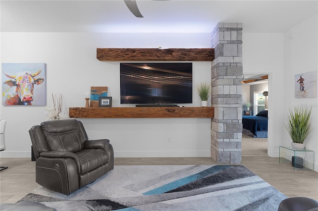 living room with a ceiling fan, decorative columns, baseboards, and wood finished floors