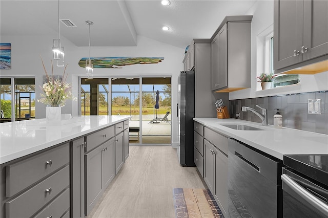 kitchen with stainless steel dishwasher, light countertops, a sink, and gray cabinetry