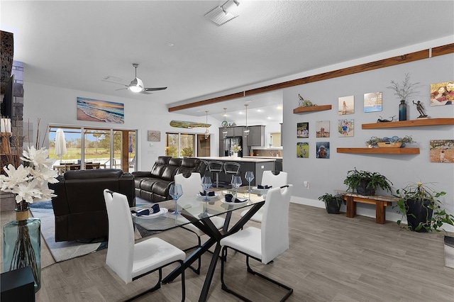 dining room with ceiling fan, a textured ceiling, wood finished floors, and visible vents