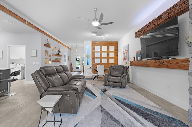 living room featuring light wood-style flooring, baseboards, and a ceiling fan