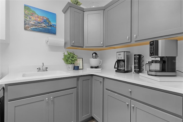 kitchen with light countertops, a sink, and gray cabinetry