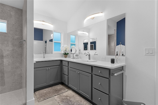 bathroom with double vanity, walk in shower, and a sink