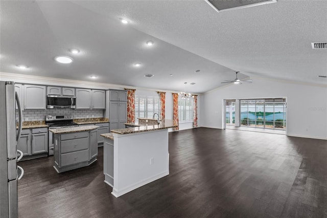 kitchen with a center island, gray cabinetry, decorative light fixtures, stainless steel appliances, and lofted ceiling