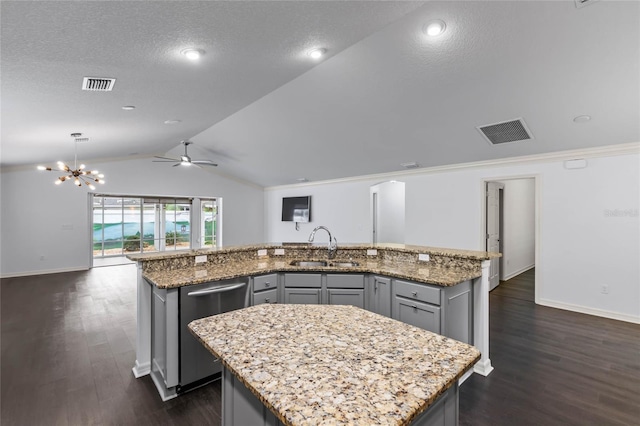 kitchen featuring stainless steel dishwasher, sink, light stone counters, a center island with sink, and gray cabinets