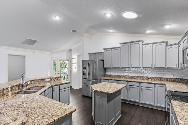 kitchen featuring stainless steel refrigerator with ice dispenser, sink, a center island, decorative backsplash, and lofted ceiling