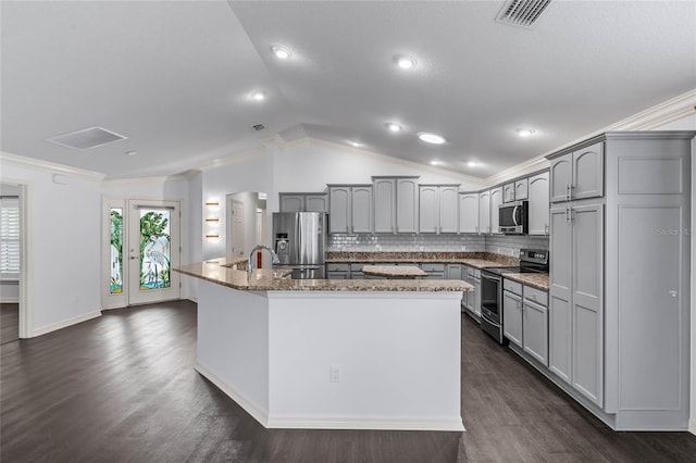 kitchen featuring stainless steel appliances, lofted ceiling, gray cabinets, and an island with sink