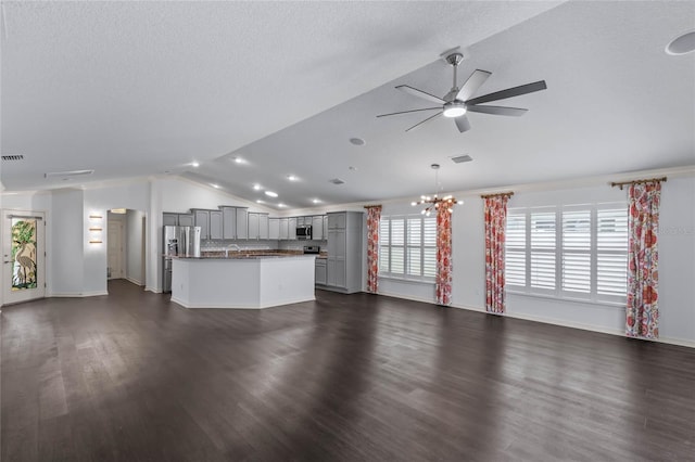 unfurnished living room featuring vaulted ceiling, sink, a textured ceiling, ceiling fan with notable chandelier, and dark hardwood / wood-style floors