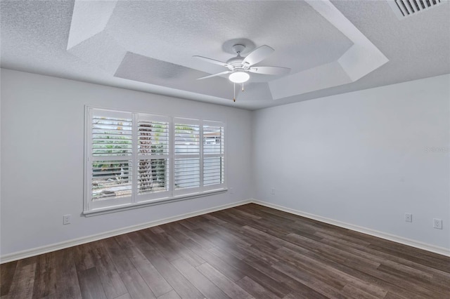 empty room featuring ceiling fan, a raised ceiling, dark hardwood / wood-style floors, and a textured ceiling