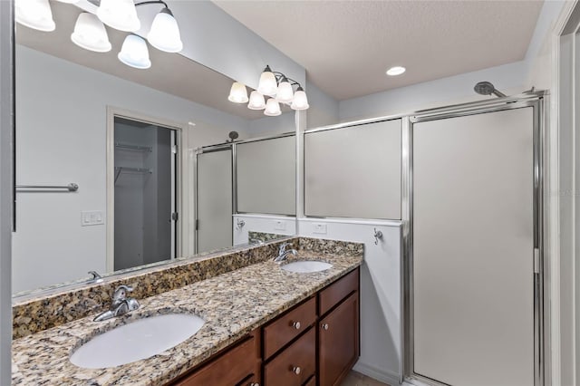 bathroom with a shower with shower door, a textured ceiling, and vanity