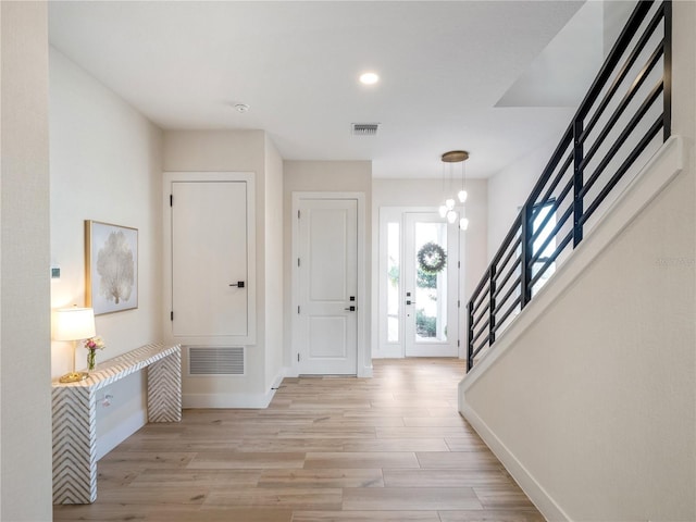 foyer entrance with a chandelier and light hardwood / wood-style floors