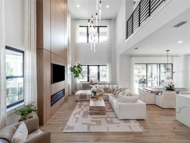 living room with a towering ceiling, a fireplace, and light hardwood / wood-style floors