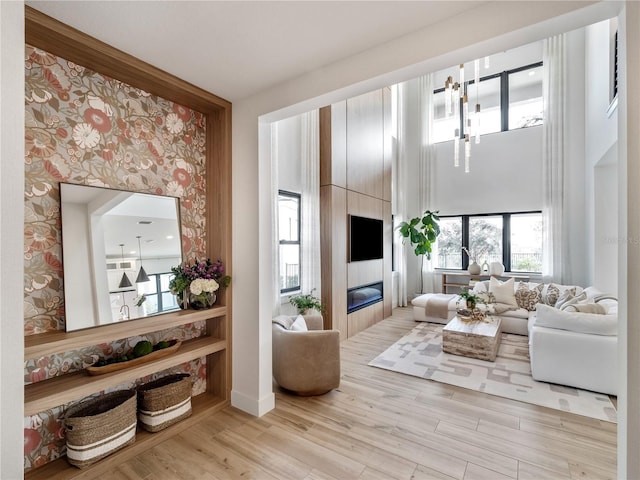 living room with a towering ceiling, a large fireplace, and light hardwood / wood-style flooring