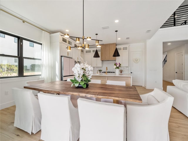 dining room featuring sink, a notable chandelier, and light hardwood / wood-style flooring