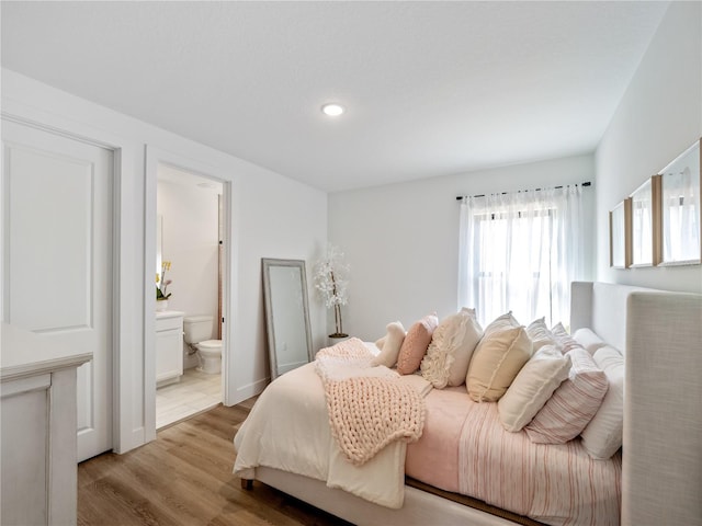 bedroom with ensuite bath and light hardwood / wood-style floors