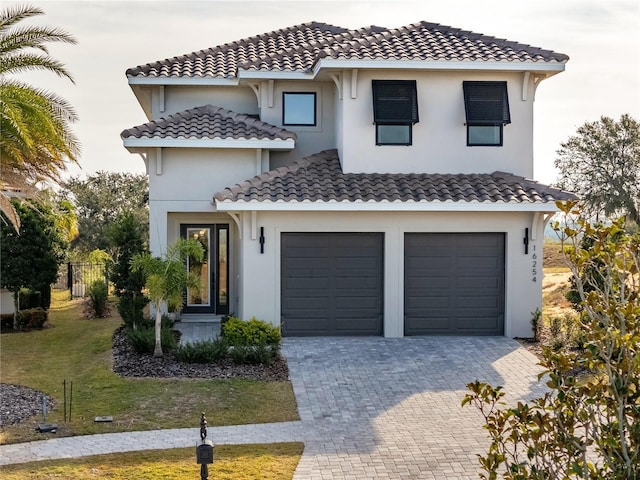 mediterranean / spanish house with a garage and a front lawn