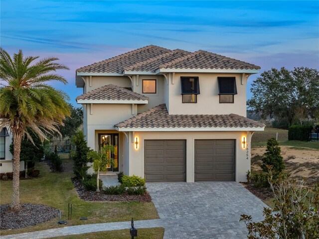 mediterranean / spanish-style house featuring a garage and a lawn