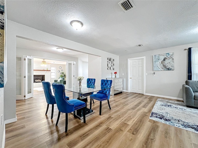 dining room featuring hardwood / wood-style flooring, a fireplace, and a textured ceiling