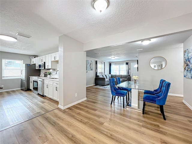 kitchen featuring sink, stainless steel appliances, white cabinets, and light wood-type flooring