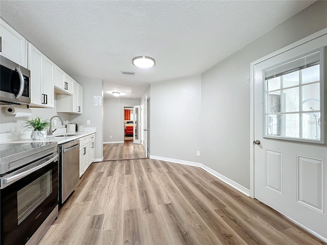 kitchen featuring white cabinetry, sink, light wood-type flooring, and appliances with stainless steel finishes