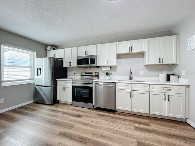 kitchen with white cabinetry, stainless steel appliances, light hardwood / wood-style floors, and sink