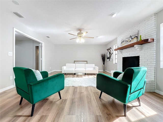 living room with ceiling fan, a textured ceiling, and light wood-type flooring