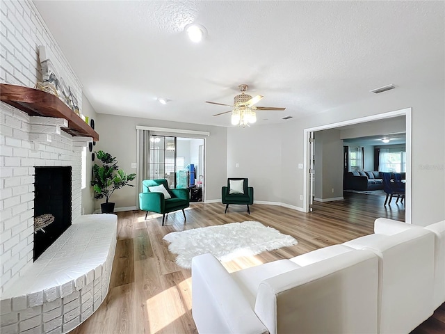 living room featuring hardwood / wood-style flooring, a fireplace, a textured ceiling, and a healthy amount of sunlight