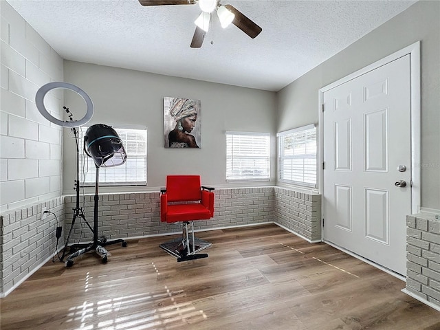 sitting room with wood-type flooring, ceiling fan, and a textured ceiling