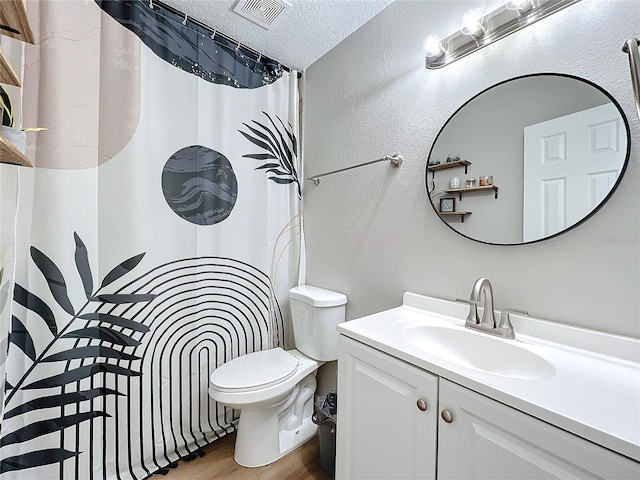 bathroom with vanity, toilet, hardwood / wood-style floors, and a textured ceiling