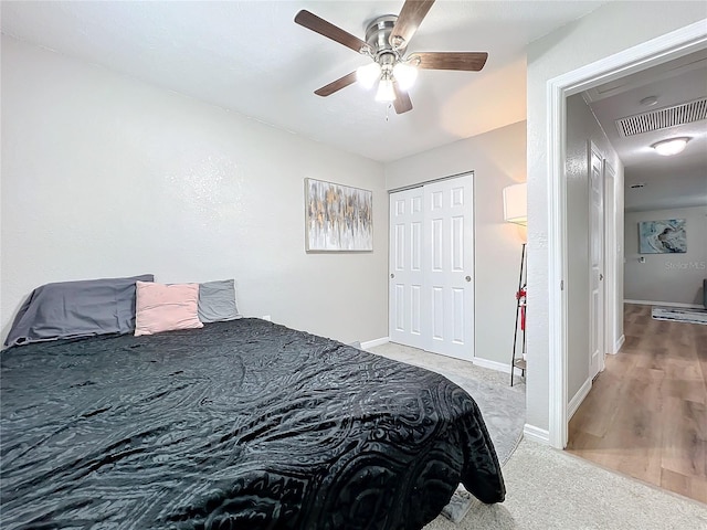 bedroom with ceiling fan, light colored carpet, and a closet