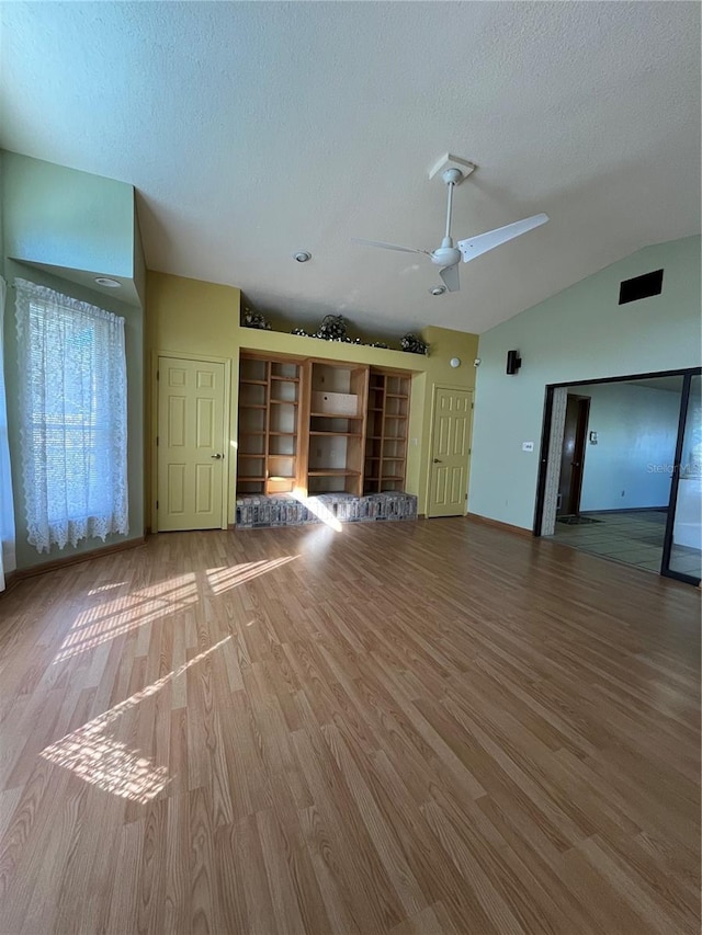 unfurnished living room with hardwood / wood-style floors, a textured ceiling, vaulted ceiling, and ceiling fan