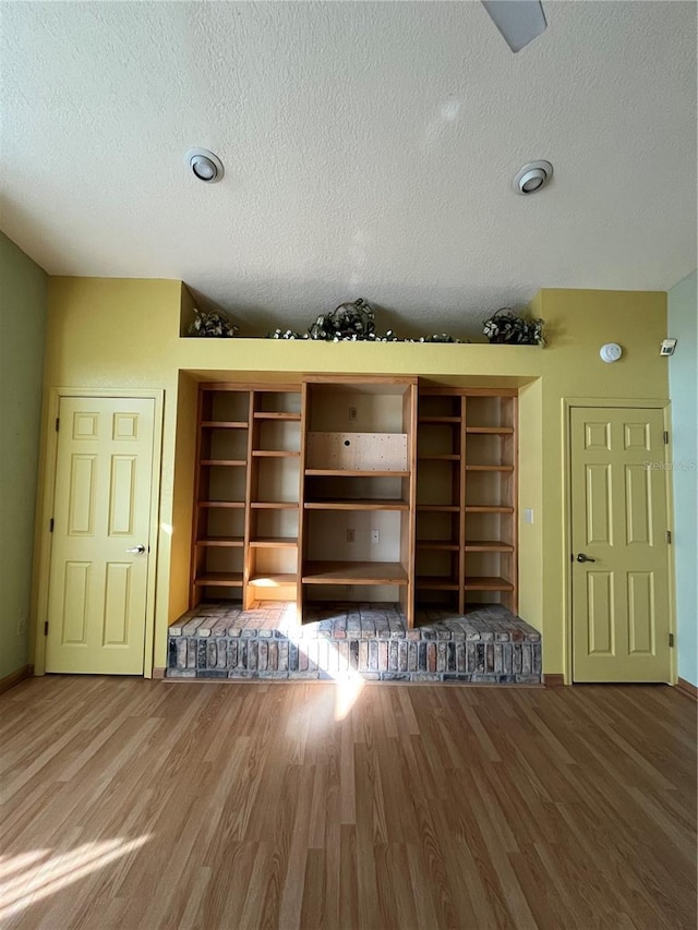 details with wood-type flooring, built in features, and a textured ceiling