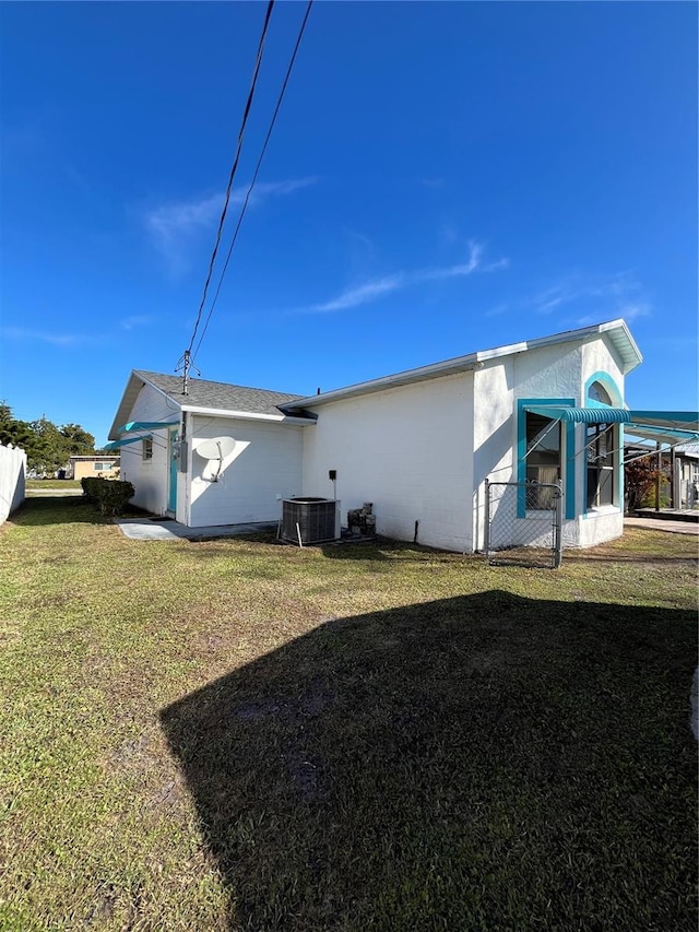 rear view of property with a lawn and central air condition unit