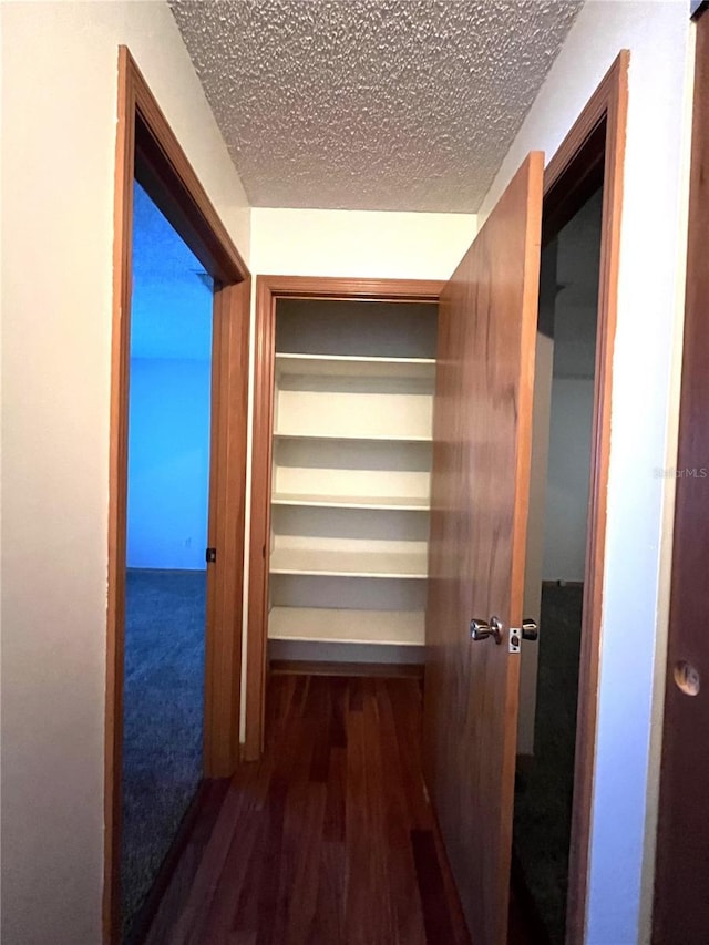 corridor with dark wood-type flooring and a textured ceiling