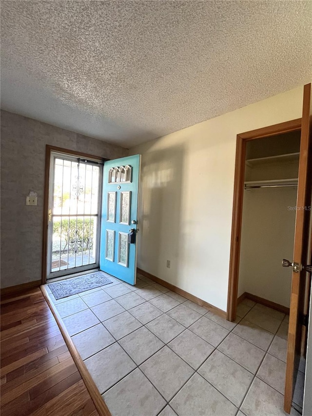 entryway with light tile patterned flooring and a textured ceiling