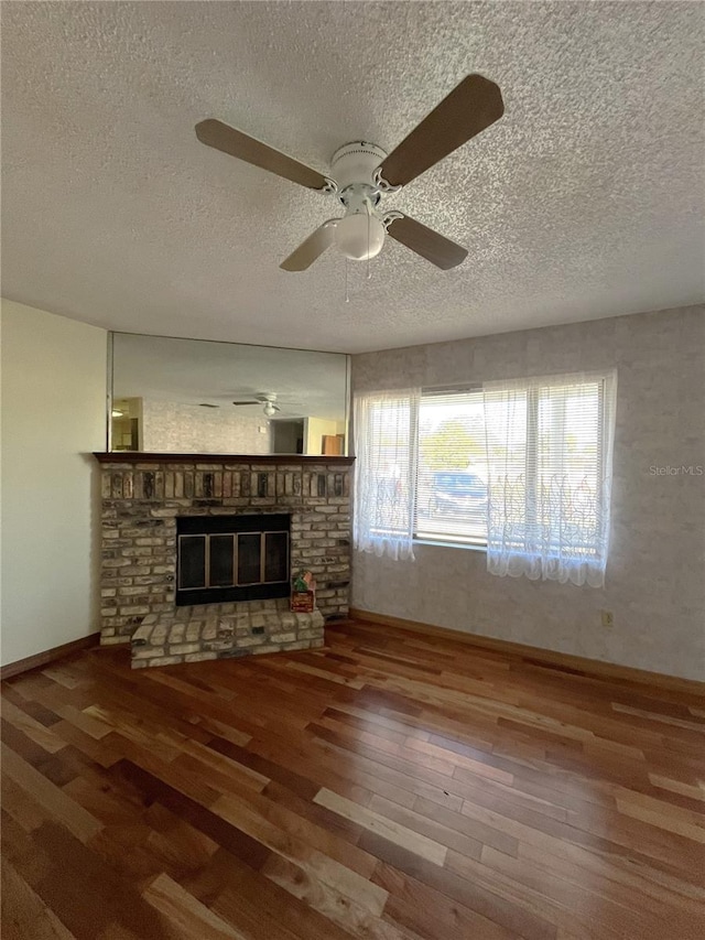 unfurnished living room featuring hardwood / wood-style flooring, a healthy amount of sunlight, a fireplace, and a textured ceiling