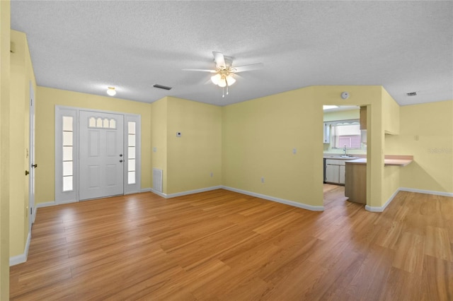 foyer entrance featuring ceiling fan, sink, a textured ceiling, and light wood-type flooring