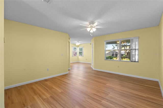 unfurnished room with a textured ceiling, ceiling fan, and light hardwood / wood-style flooring