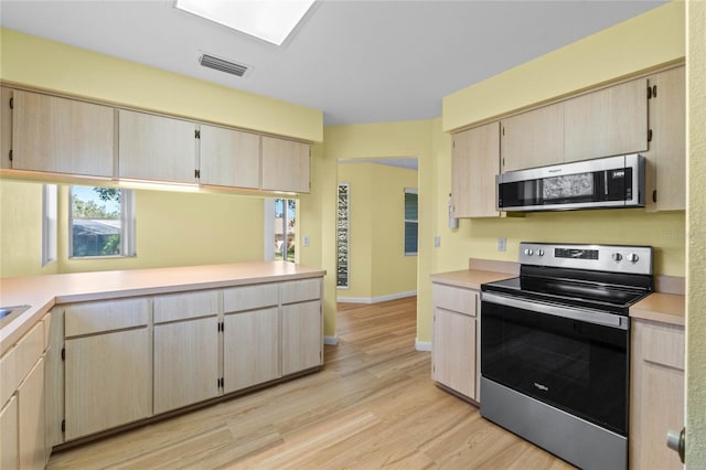 kitchen with light wood-type flooring, light brown cabinets, and appliances with stainless steel finishes