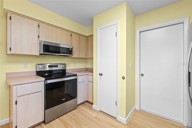 kitchen featuring appliances with stainless steel finishes, light wood-type flooring, and light brown cabinets